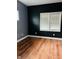 Cozy bedroom with dark accent wall, natural light from a large window, and hardwood floors at , Indianapolis, IN 46201