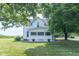 White farmhouse with covered front porch, stone surround, and mature trees at 6045 N 300 W, Greenfield, IN 46140