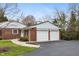 Front exterior of a two-car garage and partial brick house with a paved driveway at 625 Mulberry St, Zionsville, IN 46077