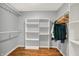 Walk-in closet with hardwood floors, white shelving, and clothes hanging on racks at 6537 Grosvenor Pl, Indianapolis, IN 46220