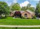 Well-kept brick home boasting a vibrant red maple tree and manicured bushes at 7732 Ashtree Dr, Indianapolis, IN 46259