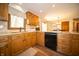 Bright kitchen boasts wood cabinets, granite countertops, a black sink and a large window at 7732 Ashtree Dr, Indianapolis, IN 46259
