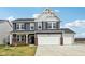 Charming two-story home featuring a three-car garage, brick accents, and blue siding against a partly cloudy sky at 8818 Tributary Dr, Indianapolis, IN 46259