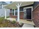 Inviting front porch features brick accents, a modern black door, and SimpliSafe security system at 8818 Tributary Dr, Indianapolis, IN 46259