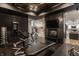 Well-equipped home gym with sleek black accents, wood ceiling, and adjacent view to the living room at 11003 Holliday Farms Blvd, Zionsville, IN 46077