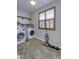 Well-lit laundry room with washer, dryer, shelves, tiled floor, and a window bringing in natural light at 12065 Watermark Ct, Indianapolis, IN 46236