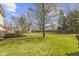 Spacious backyard featuring mature trees, a deck, a green lawn, and a wooden fence at 12161 Pebblebrooke Ct, Indianapolis, IN 46236