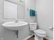 Clean half bathroom featuring a white sink, toilet, mirror, and a set of blue towels at 14974 Dry Creek Rd, Noblesville, IN 46060