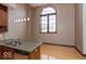 Well-lit kitchen with stainless steel sink, light wood floors, granite countertops, and large arched window at 1529 Alabama N St # H, Indianapolis, IN 46202