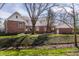Large brick home with pristine landscaping and back yard creek on an overcast day at 1591 Preston Trl, Carmel, IN 46032