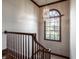 Classic staircase with wooden railings, decorative chandelier, and arched window offering natural light at 1591 Preston Trl, Carmel, IN 46032