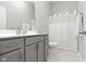 Clean, neutral bathroom with a gray vanity, modern sink, and shower with white curtain at 18271 Lake Winds Dr, Westfield, IN 46074