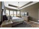 A luxurious bedroom features a tray ceiling with a crystal chandelier and natural light from the window at 18271 Lake Winds Dr, Westfield, IN 46074