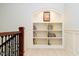 Hallway featuring an ornate railing, wainscoting and a built-in bookcase with lighting at 1997 Finchley Rd, Carmel, IN 46032