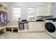 Bright laundry room with washer, dryer, built-in cabinets, countertop, and bench at 1997 Finchley Rd, Carmel, IN 46032