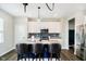 A modern kitchen featuring white cabinets, a blue island with barstool seating, and stainless steel appliances at 19992 Fenside Xing, Westfield, IN 46074