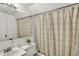 A bathroom with a shower/tub combo featuring a patterned curtain, mirror, and a sink at 214 W Elbert St, Indianapolis, IN 46217