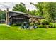 A lush green backyard featuring a screened-in porch, fire pit with Adirondack chairs, and mature trees at 224 Brierley Way, Carmel, IN 46032