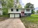 Split-level home featuring a red door and attached two-car garage with a concrete driveway at 2928 Sheffield Dr, Indianapolis, IN 46229