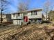 Split-level home featuring a red front door, two-car garage, and well-maintained landscaping at 2928 Sheffield Dr, Indianapolis, IN 46229