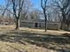 A single story home with a stone facade sits behind trees on a large front lawn at 3817 N Sheridan Ave, Indianapolis, IN 46226