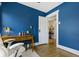 Office space featuring blue walls, wood floors, a desk, chair, and doorway to another room at 3960 N Park Ave, Indianapolis, IN 46205