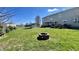Large backyard featuring a brick fire pit, lush green grass, and a trampoline at 5941 Bonneville Way, Indianapolis, IN 46237