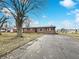 The exterior showcasing a classic brick facade and a long driveway, nestled under a blue sky with scattered clouds at 7224 Rose Dr, Indianapolis, IN 46227