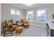 The sitting room features two accent chairs with ottomans, neutral colored walls, and bright natural light at 9184 Anthem Ave, Plainfield, IN 46168