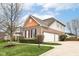 Exterior elevation showcasing the attached garage, brick facade, and manicured landscaping at 10580 Saddlestone Dr, Fishers, IN 46040