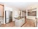 Open kitchen featuring an island, stainless steel refrigerator, and wood-look flooring at 10580 Saddlestone Dr, Fishers, IN 46040
