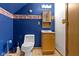 Charming bathroom with blue walls, a decorative mirror and 'Country Bath' themed wallpaper at 1243 S Morristown Pike, Greenfield, IN 46140