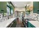 Well-lit kitchen featuring green cabinets, quartz counters, and stainless appliances and view into the dining room at 304 W 43Rd St, Indianapolis, IN 46208