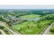 Overhead view showcases golf course, clubhouse, and tennis courts amidst green landscapes at 3989 Birkdale Dr, Carmel, IN 46033