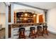 Finished basement wet bar featuring stone accents, wood shelving, granite countertops, and hardwood flooring at 3989 Birkdale Dr, Carmel, IN 46033