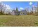 Wide backyard showcases the home's blue siding, well-maintained lawn, and the surrounding trees against a bright, cloudy sky at 4221 Millersville Rd, Indianapolis, IN 46205