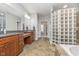 Spacious bathroom featuring dual vanities, a large mirror, and a separate glass block shower and tub area at 519 Southwind, Brownsburg, IN 46112