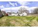 View of a home's backyard with a vast green lawn, bordered by a privacy fence and mature trees at 5849 Brouse Ave, Indianapolis, IN 46220