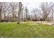 Large backyard with mature trees and a red storage building at 7806 Meadowbrook Dr, Indianapolis, IN 46240