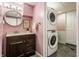 Compact bathroom featuring a modern vanity, a round mirror, and a stacked washer/dryer unit at 7806 Meadowbrook Dr, Indianapolis, IN 46240