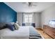 Bright bedroom with a blue accent wall, hardwood floors, comfortable bed, and dresser at 7806 Meadowbrook Dr, Indianapolis, IN 46240