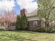 View of backyard showcasing brick house with manicured lawn and mature landscaping at 10343 Waveland Cir, Fishers, IN 46038