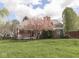 Charming backyard with large grassy area and a red brick home with a wooden porch at 10343 Waveland Cir, Fishers, IN 46038