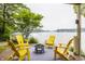 Relaxing outdoor seating area with yellow Adirondack chairs and a fire pit overlooking the serene lake at 1326 White Water Ct, Cicero, IN 46034