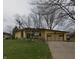 Inviting single-story home featuring mature trees, a well-kept lawn, and attached garage at 1936 Cunningham Rd, Indianapolis, IN 46224