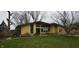Charming yellow home featuring a well-manicured lawn, mature trees, and an American flag on display at 1936 Cunningham Rd, Indianapolis, IN 46224