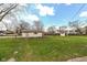 View of a spacious backyard highlighting the lush lawn, storage shed, and mature trees with a blue sky above at 202 Rainbow Blvd, Indianapolis, IN 46234