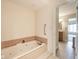 A bathroom showing a jetted tub with tile surround and safety bar, offering a relaxing space with easy access to the adjacent room at 3334 Eden Village Pl, Carmel, IN 46033