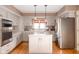Bright kitchen with stainless steel appliances, an island with cooktop, and wooden flooring throughout at 3334 Eden Village Pl, Carmel, IN 46033