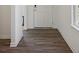 Hallway leading to the front door featuring wood-look flooring and white trim at 4712 E Shadowbrook Dr, Camby, IN 46113